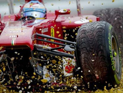 The damaged Ferrari of Fernando Alonso comes grinding to a halt in a gravel trap.