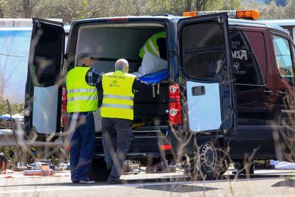 Authorities place the body of a victim into a hearse on the Spanish AP-7 motorway near Freginals.