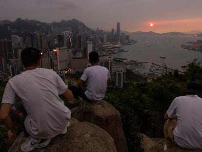 Mainland Chinese tourists look at sunset from a hill in Hong Kong