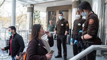 Security guards ask for documents from people seeking to enter a courtroom in Madrid.