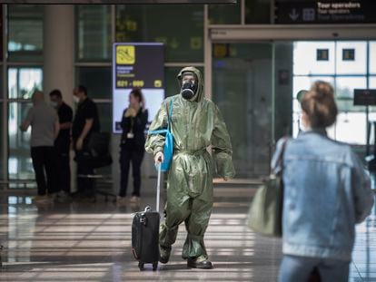 A passenger arrives from London in Barcelona’s El Prat airport on Friday wearing military coveralls and a gas mask.
