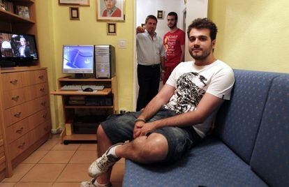 David S&aacute;nchez, 27 years old sits in his room with his brother V&iacute;ctor (22), behind, and their father Francisco.