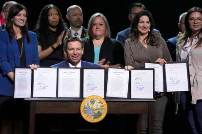 Florida Gov. Ron DeSantis holds up bills he signed during a bill signing ceremony at the Coastal Community Church at Lighthouse Point