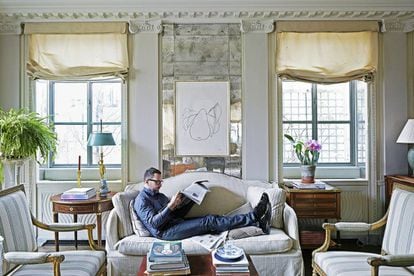 James Costos, in his New York residence underneath an Ellsworth Kelly work titled ‘Pear.’ “I love to lie on the sofa with my feet up,” he admits. He is wearing a GIORGIO ARMANI shirt, APC jeans, a LOUIS VUITTON belt and GIVENCHY shoes.