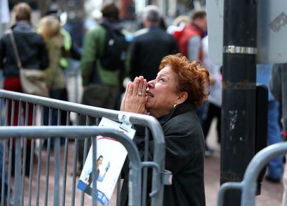 A woman kneels and prays at the scene of the first explosion on Boylston Street near the finish line of the 117th Boston Marathon on April 15, 2013