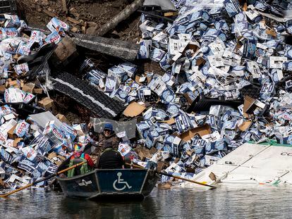 A group of fishermen claims a bottle of beer from a derailed railcar on the banks of the Clark Fork River near Quinn's Hot Springs, in St. Regis, Montana, on April 2, 2023.
