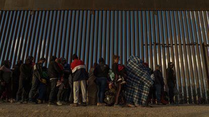 Migrants line up against the border wall to surrender to immigration officials after breaching a razor wire-laden fence along the bank of the Rio Grande in El Paso, Texas, U.S., March 25, 2024.