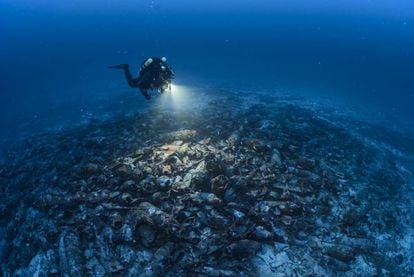 A diver examines the remains, which are covered by hundreds of amphorae.
