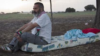 Juan Manuel S&aacute;nchez Gordillo sits on the mattress where he is sleeping on land owned by the Defense Ministry. 