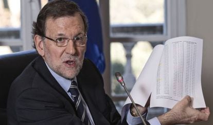 Rajoy shows journalists unemployment data.