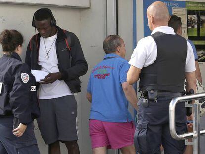 Two French police officers intercept a migrant at the border.