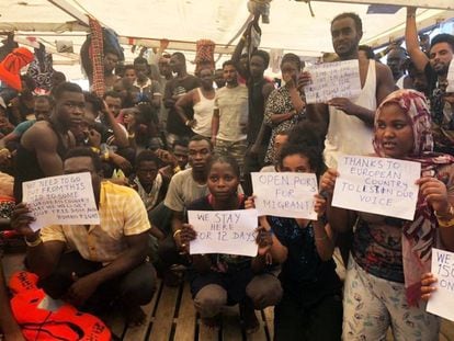 The rescued migrants hod up signs calling for help.