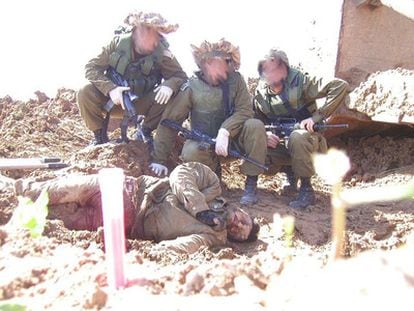Israeli soldiers pose with the body of a Palestinian.