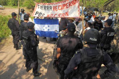 Police watch protestors take over a plot of land in Honduras.