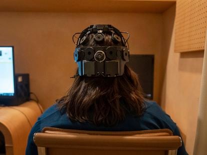 Emily Hollenbeck, a deep brain stimulation therapy patient, demonstrates an EEG device that records brain activity as she reacts to short videos at Mount Sinai’s “Q-Lab” in New York on Dec. 20, 2023.