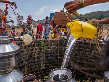 A villager pours water into a canister as others gather around a well to draw water in Telamwadi, northeast of Mumbai, India, May 6, 2023. T