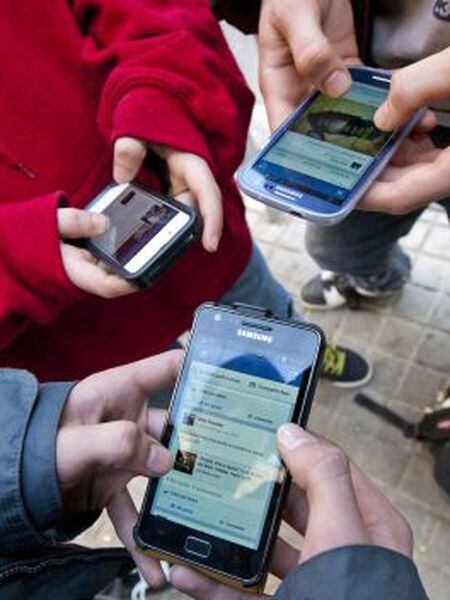 Three youngsters connect to the internet with their smartphones.