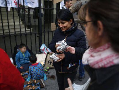Locals give food to a Peruvian family seeking a bed outside Madrid’s Samur Social.