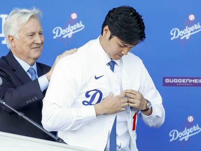 Mark Walter, a Dodgers owner, assists Ohtani in donning the Los Angeles team's jersey.