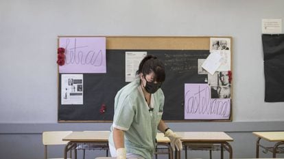 A cleaner wearing a mask prepares a classroom in Barcelona.