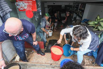 Locals clear out water from a flooded shop in Arganda del Rey in Madrid region.