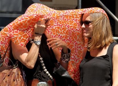 Two women try to shelter from the heat in downtown Madrid.