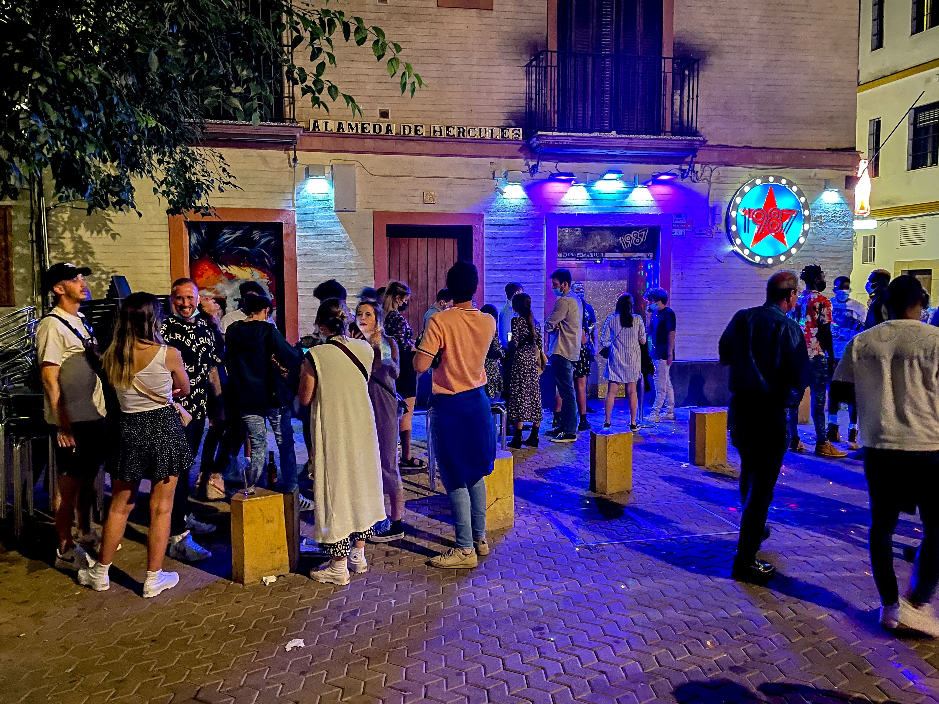 A line of people waiting outside a nightclub in Seville.