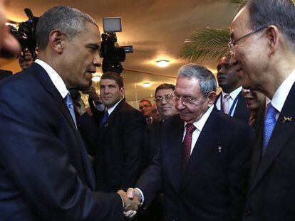 Barack Obama greets Raúl Castro.