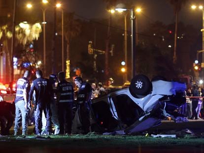Israeli police and emergency service stand around a car involved in an attack in Tel Aviv, Israel, Friday, April 7, 2023.