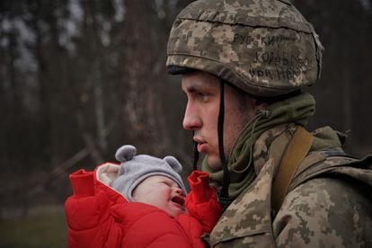A Ukrainian soldier hands a baby to its mother after crossing the rubble of a bridge in Irpin, near the capital Kyiv, on March 5, 2022.