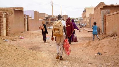 People carry their belongings as they walk down a street in Omdurman, the twin city of the war-torn capital of Sudan, on Monday.