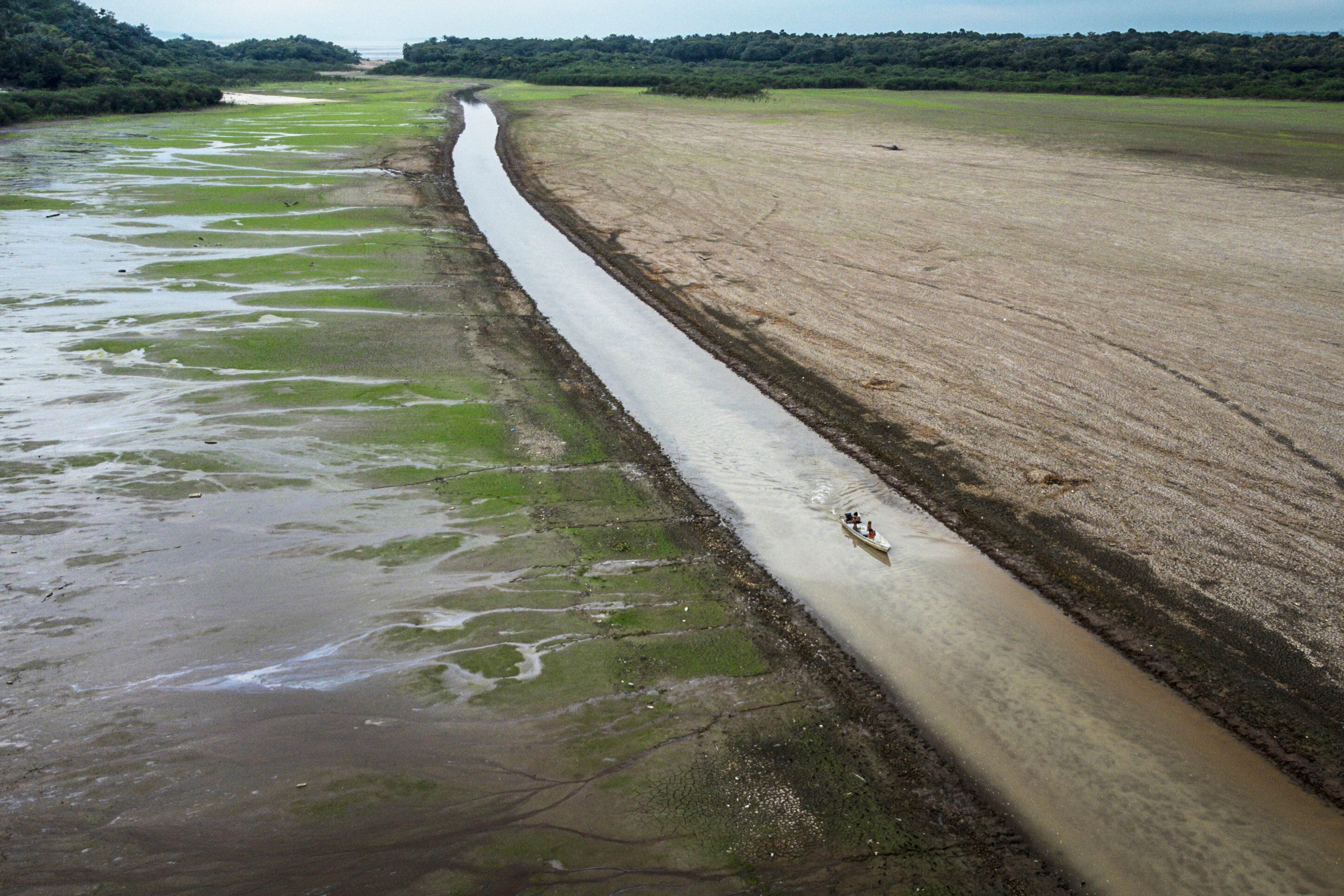 A boat navigates a narrow channel through a dry Lake Aleixo in Manaus, Brazil; October 25, 2022.