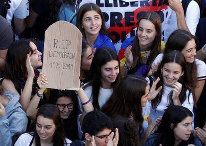 A protester holds a sign reading “R.I.P. Democracy 1975-2019” at a student protest in Barcelona.