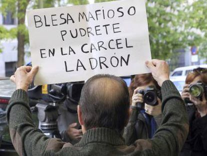 A protestor carries a sign reading: “Blesa, you mobster, rot in jail you thief.”