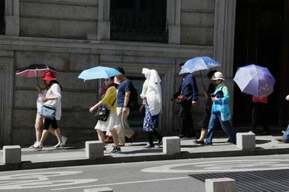 Tourists use umbrellas to keep the sun off in Madrid.