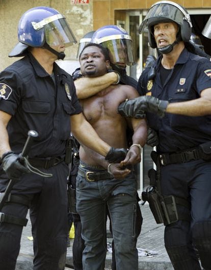 The police detain a Nigerian man after Monday's riot.