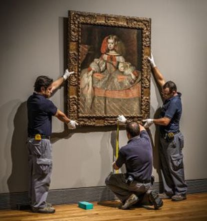 Museum staff take measurements for the hanging of one of the paintings.