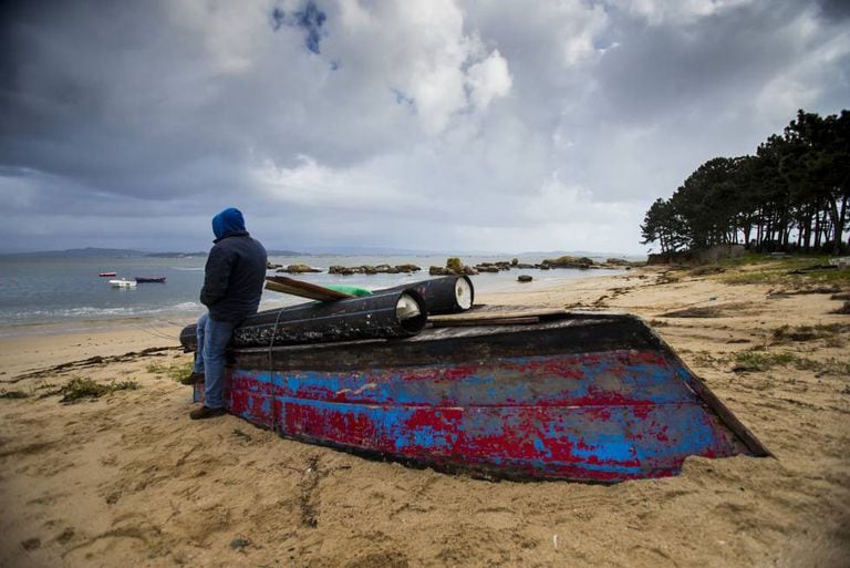 A poacher on the Arousa estuary leans on a boat used for the nightly raids.