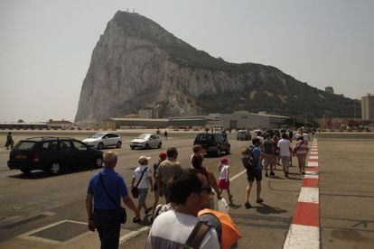 Pedestrians and drivers cross the tarmac of the Gibraltar airport in front of the Rock.