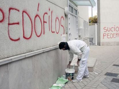 A painter covers up graffiti in the parish where suspect Father Román worked.