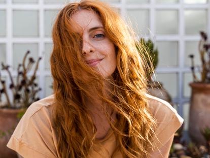 Portrait of a smiling redheaded young woman on a terrace.