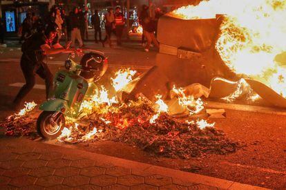 A separatist demonstrator puts a scooter into a fire during a protest in Barcelona.