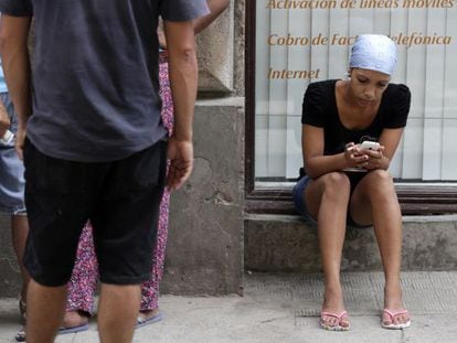 A woman uses a cellphone on a street in Havana.