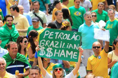 A woman holds up a sign reading “Brazilian Oil $$hame” during Sunday's protests held against Rousseff’s policies.