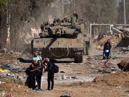 Injured Palestinians pass an Israeli tank while fleeing south on the outskirts of Gaza City; November 24, 2023.