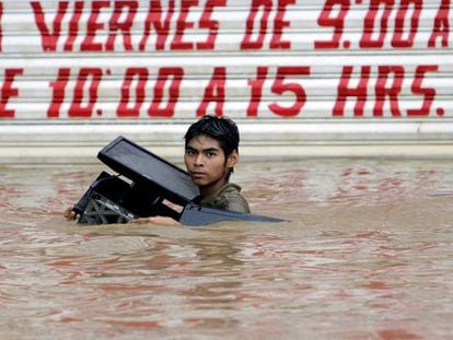 A young man carrying a computer wades through a flooded street in Acapulco.