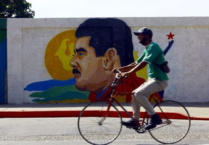 A man cycles past a mural of Venezuelan leader Nicolás Maduro.