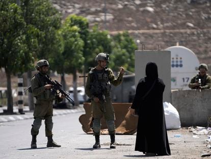 Israeli soldiers speak to a Palestinian woman near the site of an alleged car-ramming attack near Beit Hagai, a Jewish settlement in the hills south of the large Palestinian city of Hebron, Wednesday, Aug. 30, 2023.