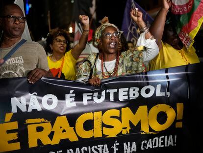 People hold a banner with a message that reads in Portuguese; "It isn't football, it is racism" during a protest in Rio de Janeiro, Brazil, on May 25, 2023.