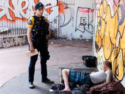 An officer stands next to a person who appears to be passed out on May 18, 2023, in downtown Portland, Oregon.